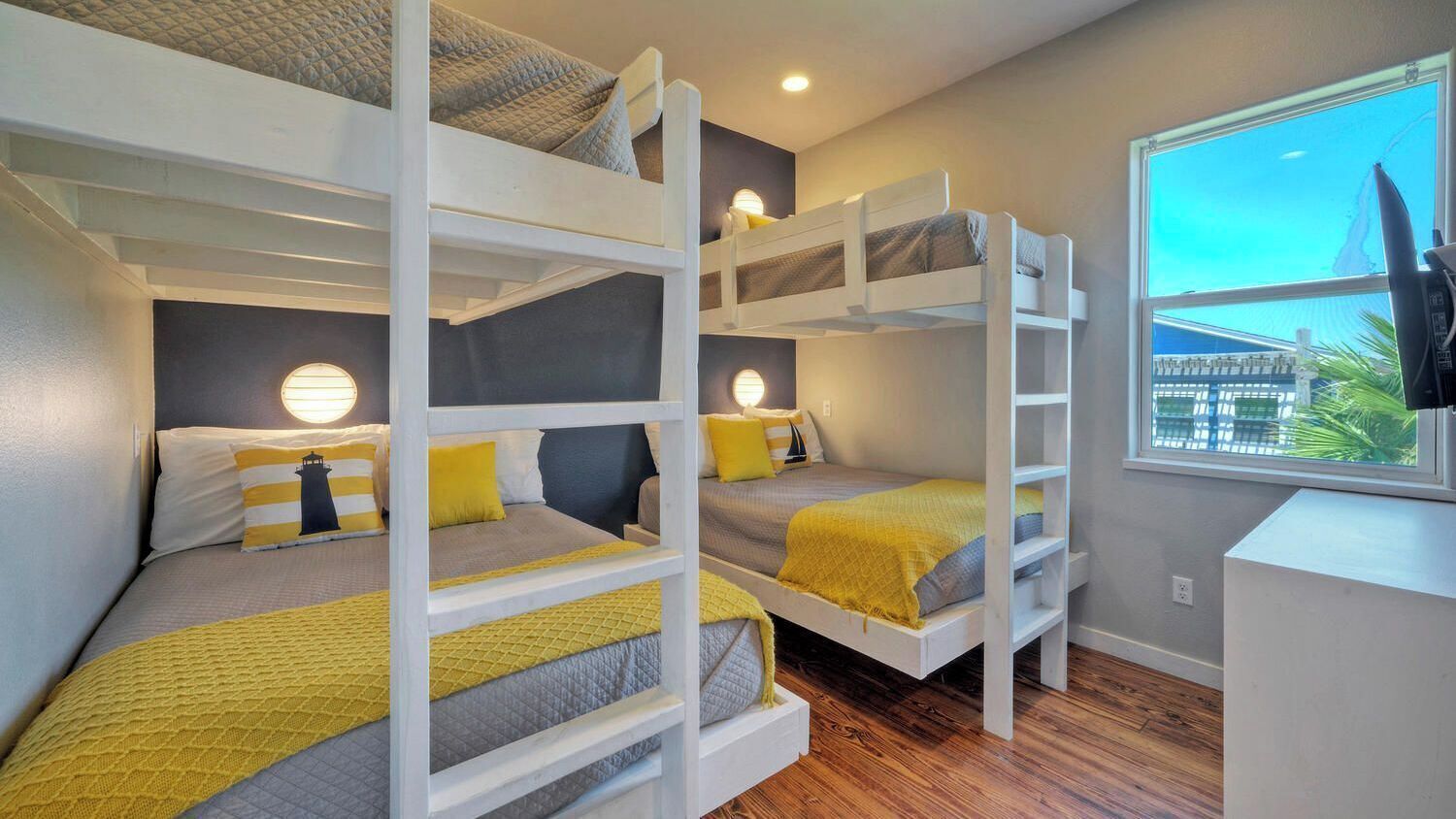 Een slaapkamer met een stapelbed, een bureau en een lamp, met uitzicht uit het raam.