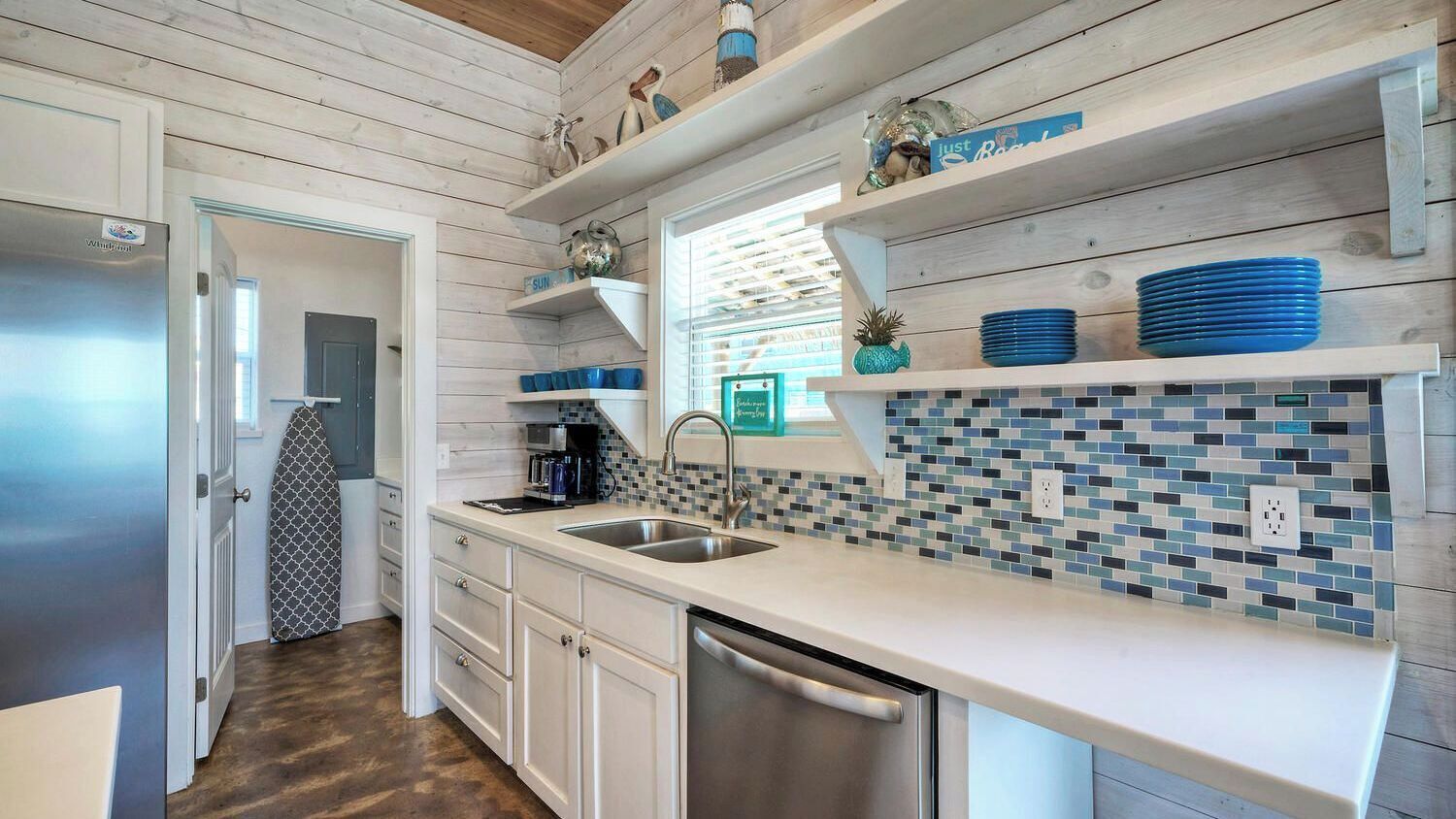 A kitchen with white cabinets, a stainless steel dishwasher, and a tiled backsplash.