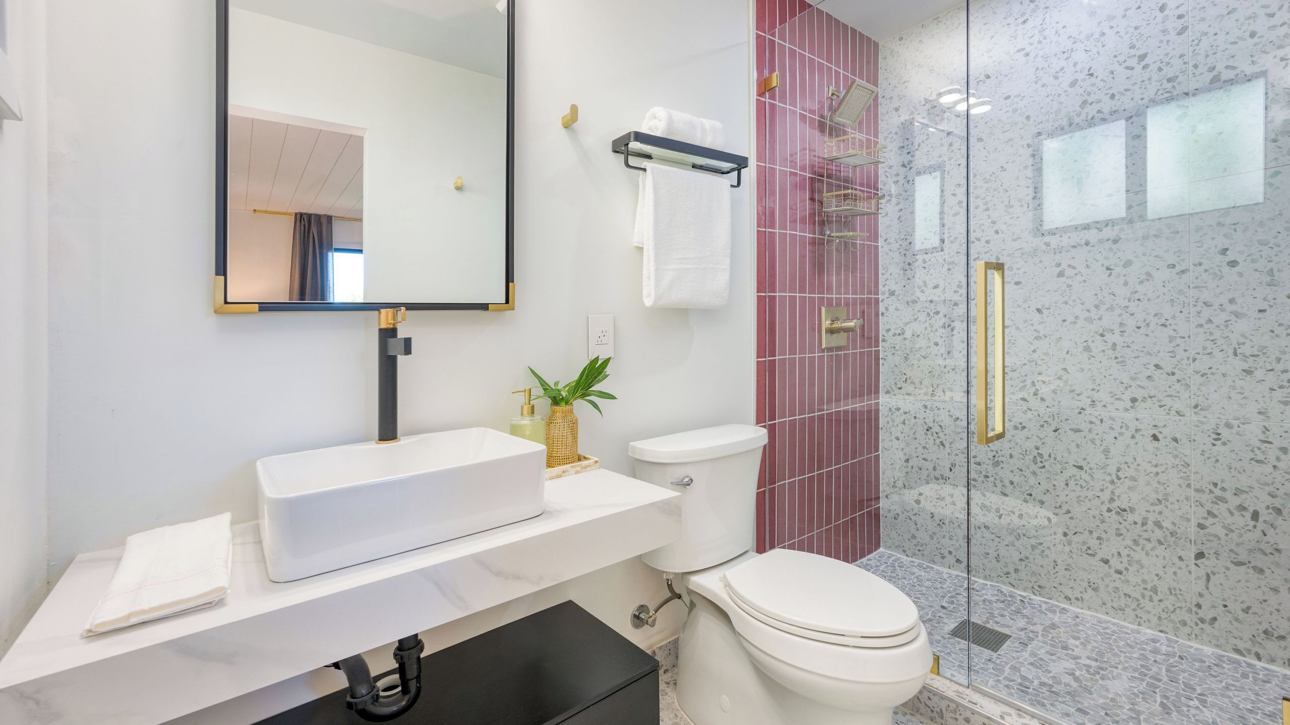 A modern bathroom with a white sink, toilet, and shower area.
