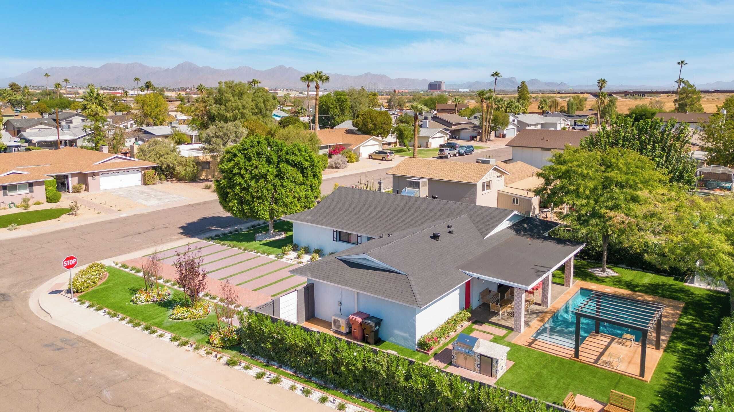 A residential area with houses, a stop sign, a swimming pool, and a mountain range in the background.