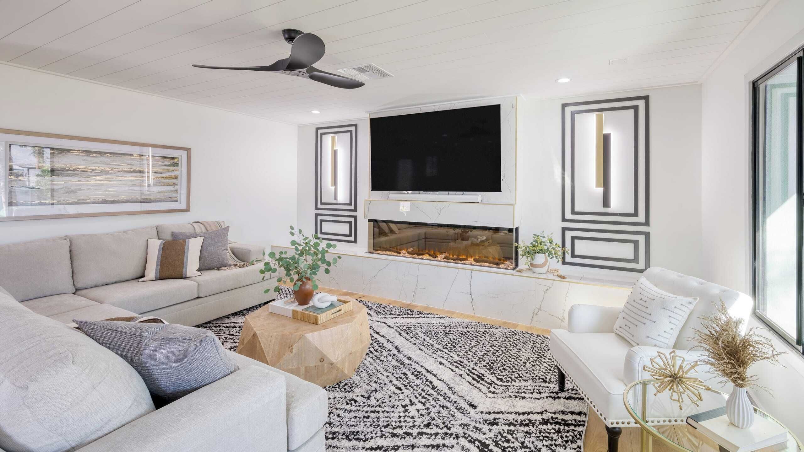 A modern living room with a sofa, coffee table, and a flat-screen TV mounted above a fireplace.
