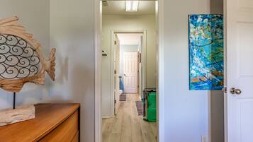 A hallway with a wooden dresser, a decorative wall piece, and a door with a blue abstract painting.