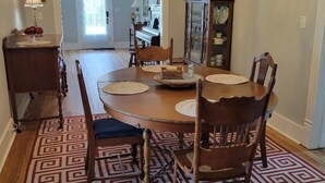 A dining area with a round table, chairs, a chandelier, and a patterned rug. - M G Richardson Bed & Breakfast (Richland)