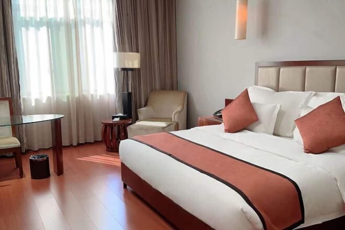 Ein Hotelzimmer mit einem großen Bett, einem Sessel, einem kleinen Tisch und einer Lampe.