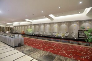 Eine Hotelhalle mit einer langen Rezeption, einem rot belegten Teppichbereich und einer Wand mit Dekorationselementen.