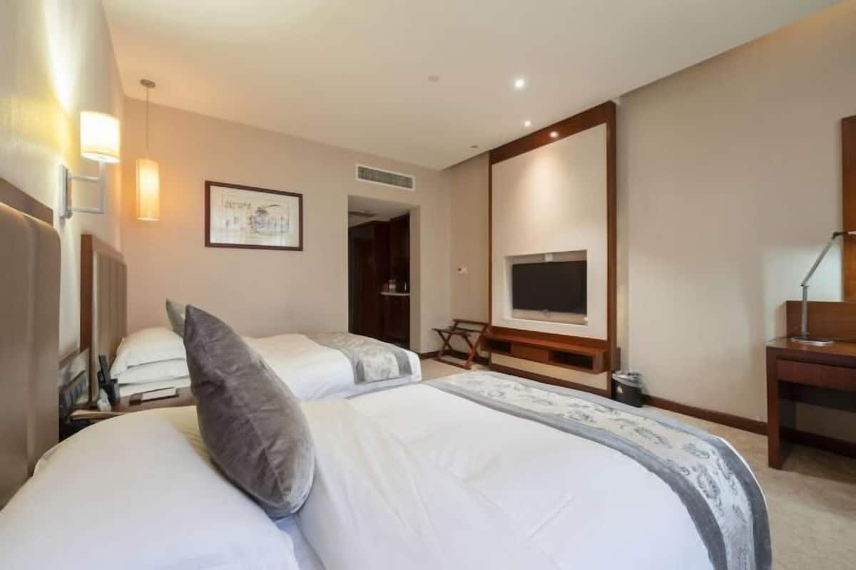 Ein Hotelzimmer mit zwei Betten, einem Fernseher, einem Schreibtisch und einem Stuhl.