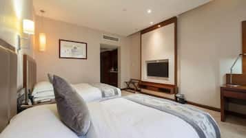 A hotel room with two beds, a TV, a desk, and a chair.