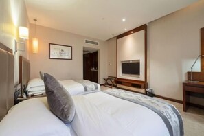 Habitación de hotel con dos camas, televisión, escritorio y una silla.