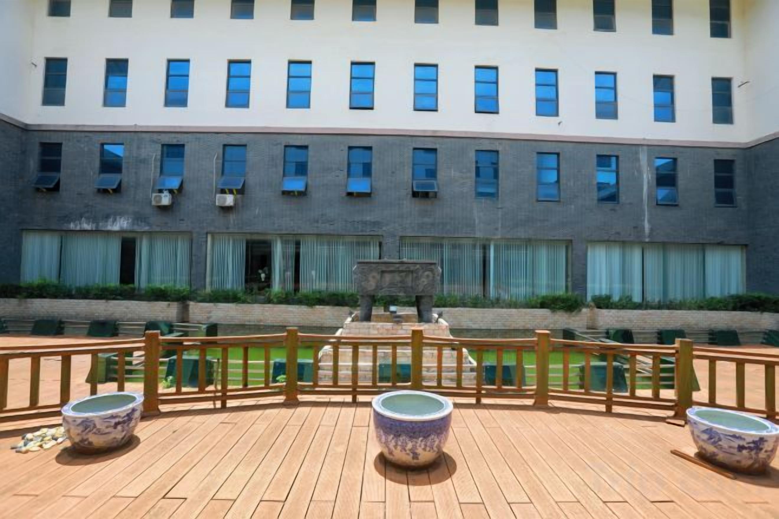Ein Gebäude mit Innenhof, Holzterrasse und Wasserspiel.