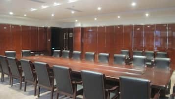 A conference room with a long table surrounded by chairs, wooden paneling on the walls, and recessed ceiling lighting.
