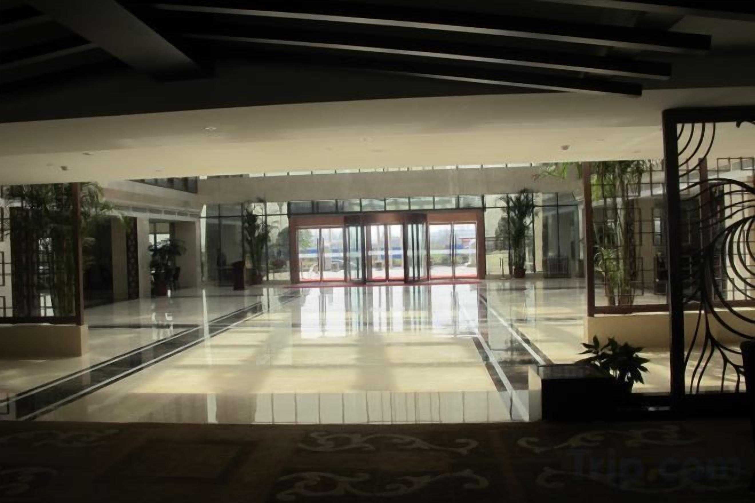 Um lobby amplo com entrada de vidro, piso estampado e design moderno no teto.