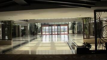 Um lobby amplo com entrada de vidro, piso estampado e design moderno no teto.