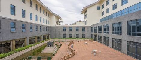 A courtyard with a circular seating area, surrounded by buildings with multiple windows and balconies.