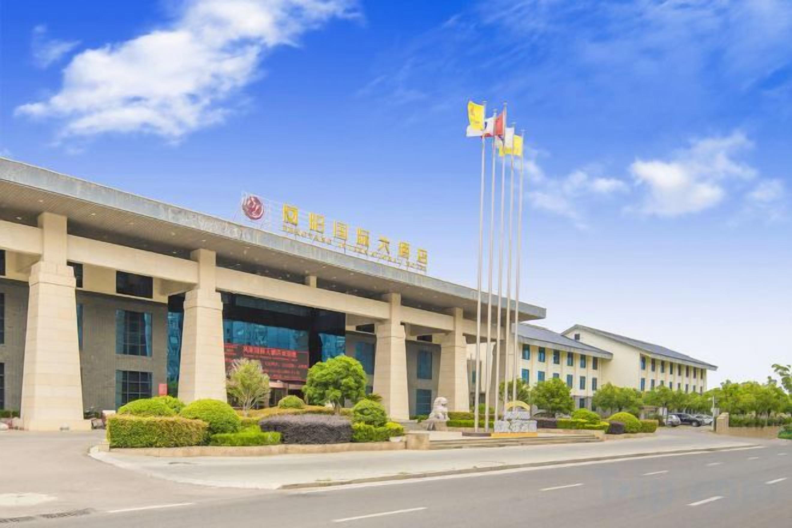 A building with a large entrance, multiple flags, and a clear sky.