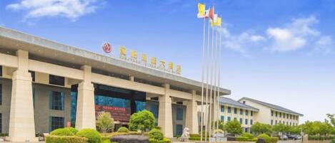 A building with a large entrance, multiple flags, and a clear sky.