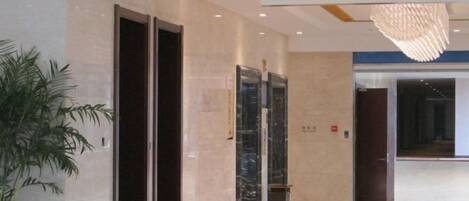 An interior corridor with a modern elevator, a directional sign, and a potted plant.