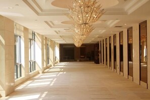 A long, well-lit corridor with a large chandelier, large windows, and doors on one side. - Fengyang International Hotel (Fengyang)