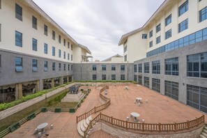 A courtyard with a central open area, surrounded by buildings with large windows and a brick floor. - Fengyang International Hotel (Fengyang)