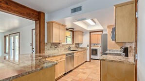 Una cucina moderna con mobili in legno, piani di lavoro in granito ed elettrodomestici integrati.
