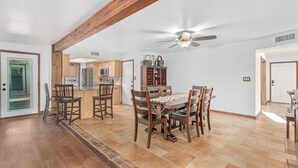 Un'ampia cucina con mobili in legno, un'area pranzo con un tavolo e sedie grandi e una ventola a soffitto.