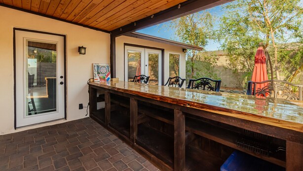 Patio esterno con tavolo in legno, sedie e bersaglio da freccette.