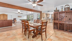 Un'ampia zona pranzo con un tavolo e sedie in legno, una ventola a soffitto e una cucina sullo sfondo.