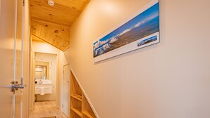 A hallway with wooden flooring, a wooden staircase, and a framed picture on the wall.