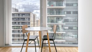 A modern room with a large window, two chairs, and a round table. - Bright Canary Wharf 1BR, steps to South Quay light rail, by Blueground (London)