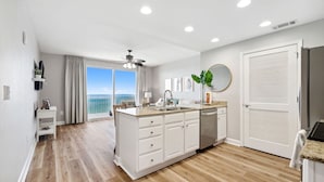A modern kitchen with a large island, white cabinetry, and a view to the outside.