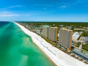 A beachfront hotel with multiple high-rise buildings, a sandy beach, and a clear blue ocean. - Splash Resort! Aqua park, lazy river, pools, ocean front! Free Beach Chairs! (Panama City Beach)