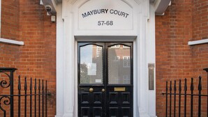 L’entrée de Maybury Court se trouve dans un bâtiment en briques, doté d’une porte noire à deux battants et d’une enseigne au-dessus.