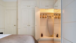 Une chambre à coucher avec un lit, une armoire blanche et un portant à vêtements.