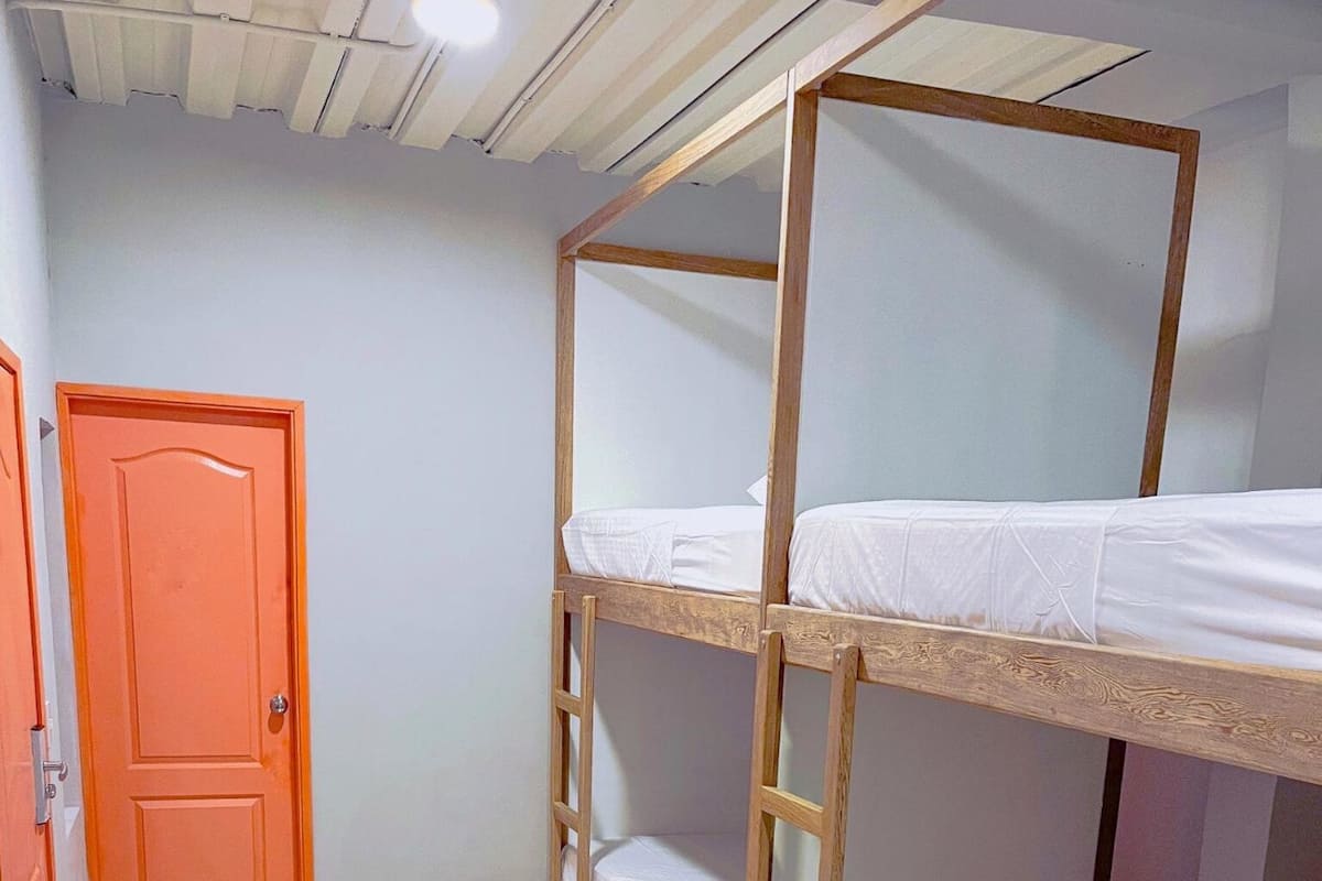 A room with bunk beds, a wooden ladder, and an orange door.
