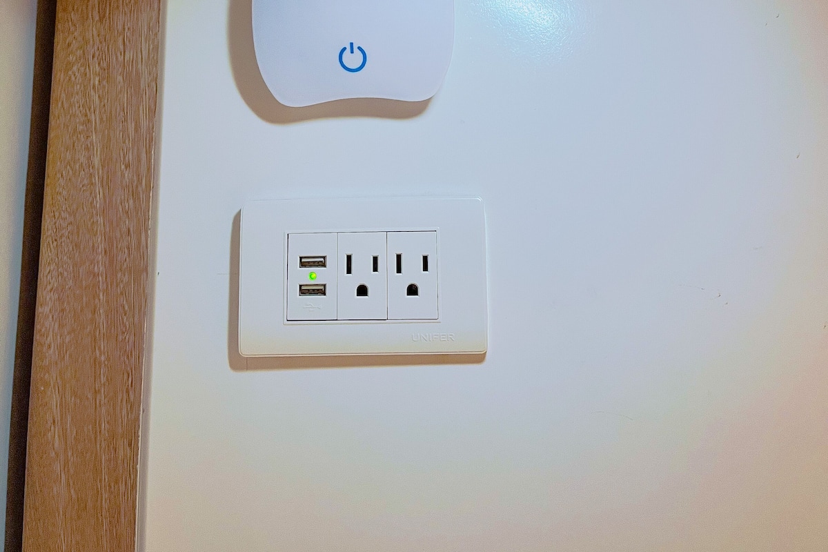 A power strip with multiple outlets and USB ports, mounted on a white wall.