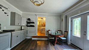 A modern kitchen with built-in cabinets, a dining area with a glass table, and a large window with a view. - RockSide Suite: Stairs & Ramp Access • Masters Tournament • Lake Getaways (Appling)