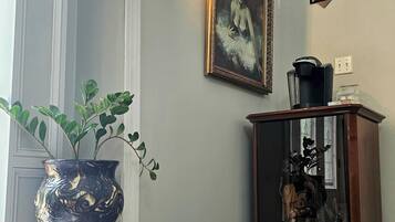 Une pièce comprenant un grand vase, un tableau encadré, un meuble avec un miroir et un luminaire fixé au mur.