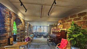 A cozy room with a piano, wicker chairs, and a large potted plant. - LAM Apartment & Hotel Danang (Da Nang)