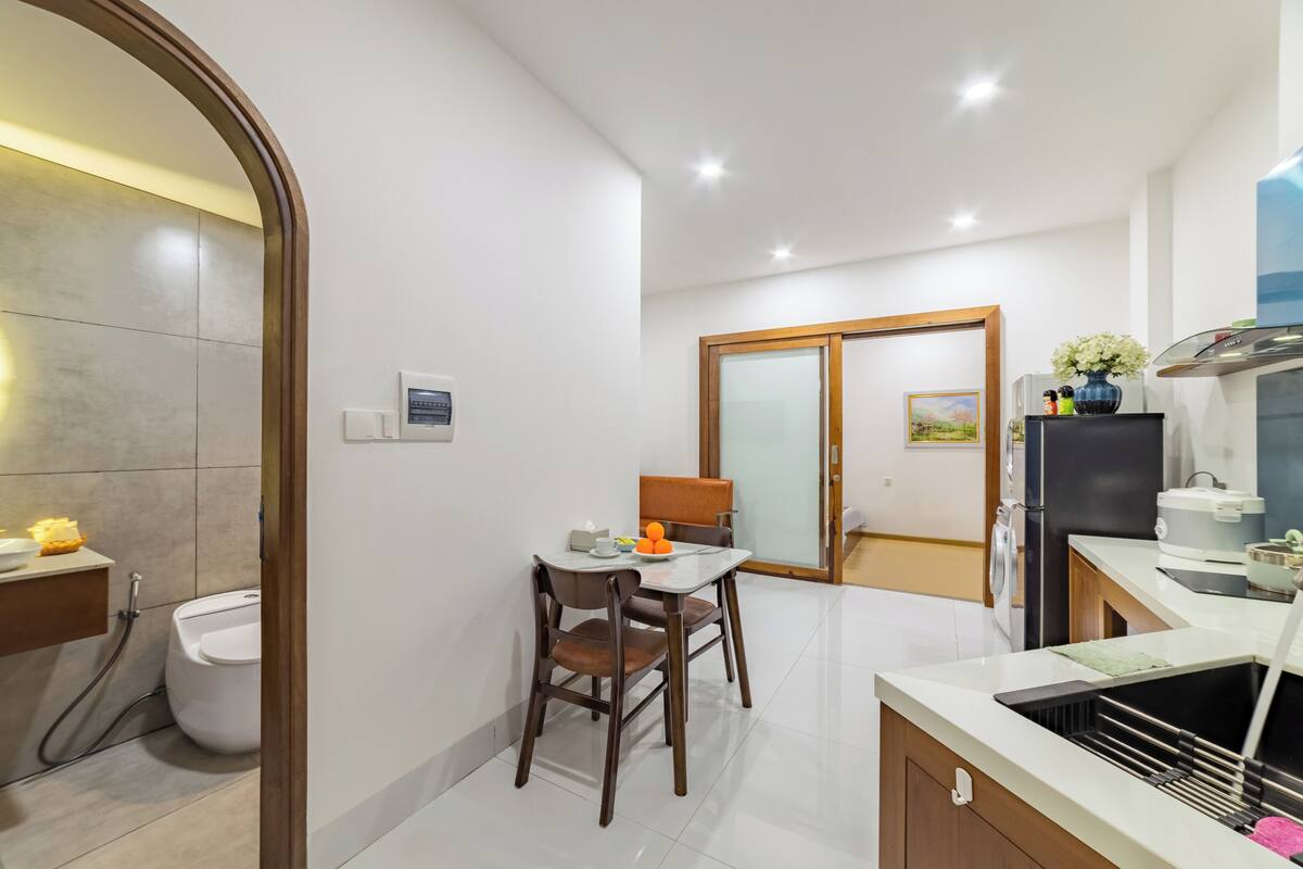 A modern kitchen with a dining area, a built-in oven, and a refrigerator.