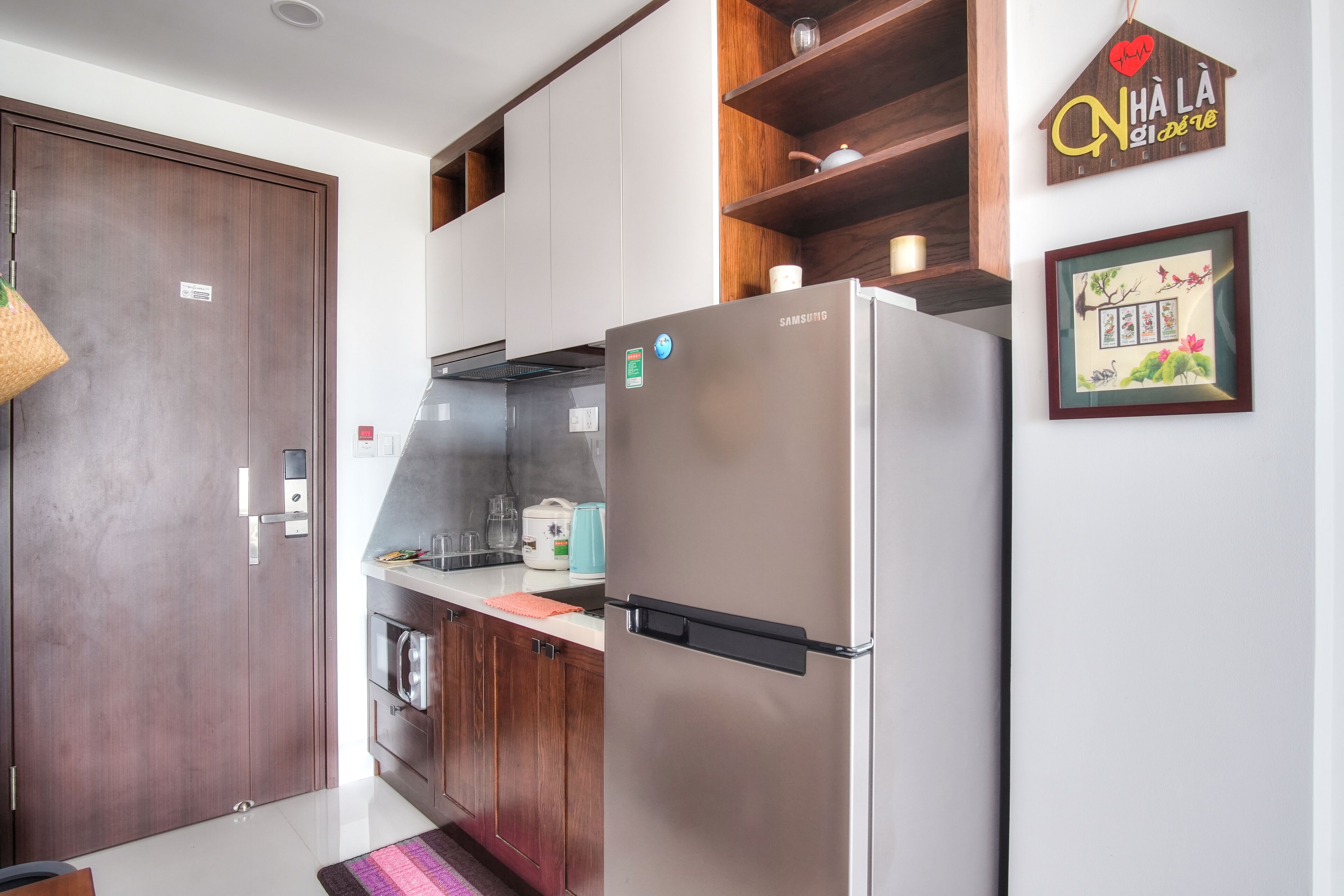 A modern kitchen with a stainless steel refrigerator, wooden cabinets, and a hanging basket.