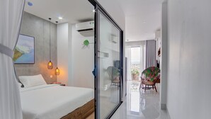A modern bedroom with a glass door leading to a balcony, a bed with a wooden headboard, and a painting on the wall. - LAM Apartment & Hotel Danang (Da Nang)
