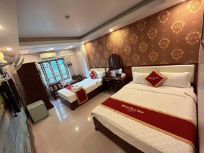 A hotel room with a large bed, two smaller beds, a desk, a chair, a wardrobe, and a mirror. - Hotel Nam Sơn 1 (Hai Phong)