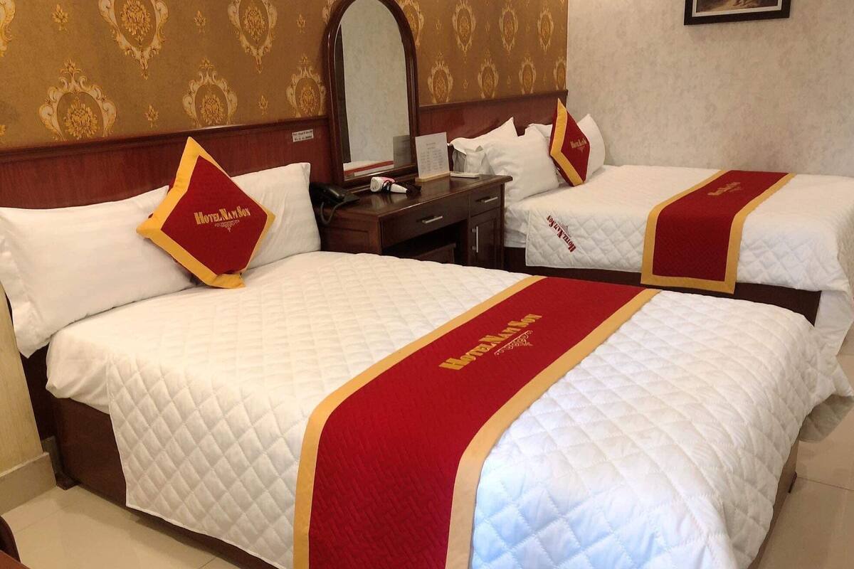 A hotel room with two beds, each with a red and gold bedspread and matching pillows.
