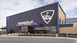 Un bâtiment moderne avec une grande enseigne sur laquelle on peut lire « TOPGOLF TOPTRACER ».