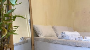 A bedroom with a bed, a mirror, and a potted plant. - Malayah Hostel (General Luna)