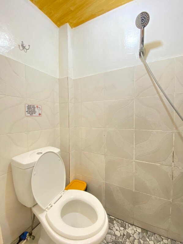 Un baño pequeño con inodoro, ducha y piso de baldosas.