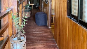 A wooden corridor with a bench, a wicker plant pot, and a hanging lantern. - Malayah Hostel (General Luna)