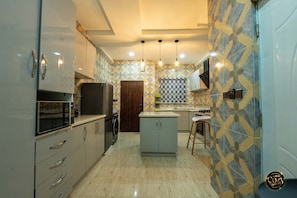 Cozinha moderna com eletrodomésticos de aço inoxidável, uma ilha central e paredes com ladrilhos estampados.