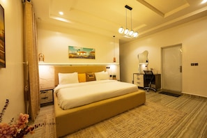 Quarto de hotel moderno com uma cama grande, mesas de cabeceira, uma escrivaninha e uma cadeira.