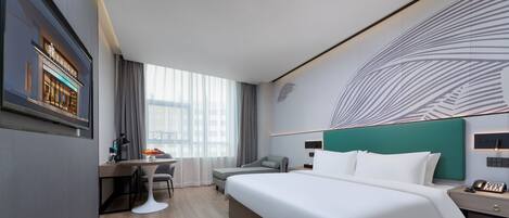 A modern hotel room with a large bed, a desk, a chair, and a view of the city through large windows.