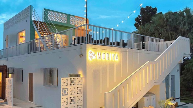 Un edificio moderno con un balcón, una escalera y un letrero que dice "MORIYA".